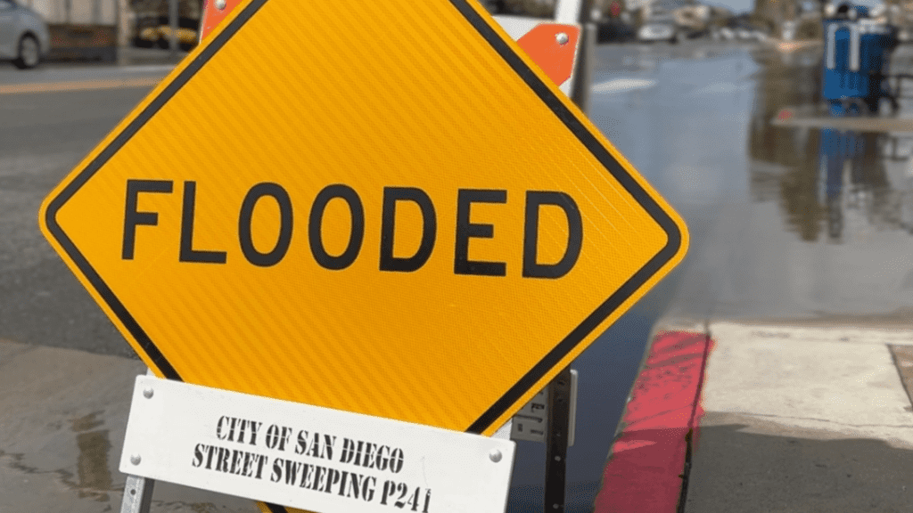 A City of San Diego sign "Flooded" installed on a flooded street